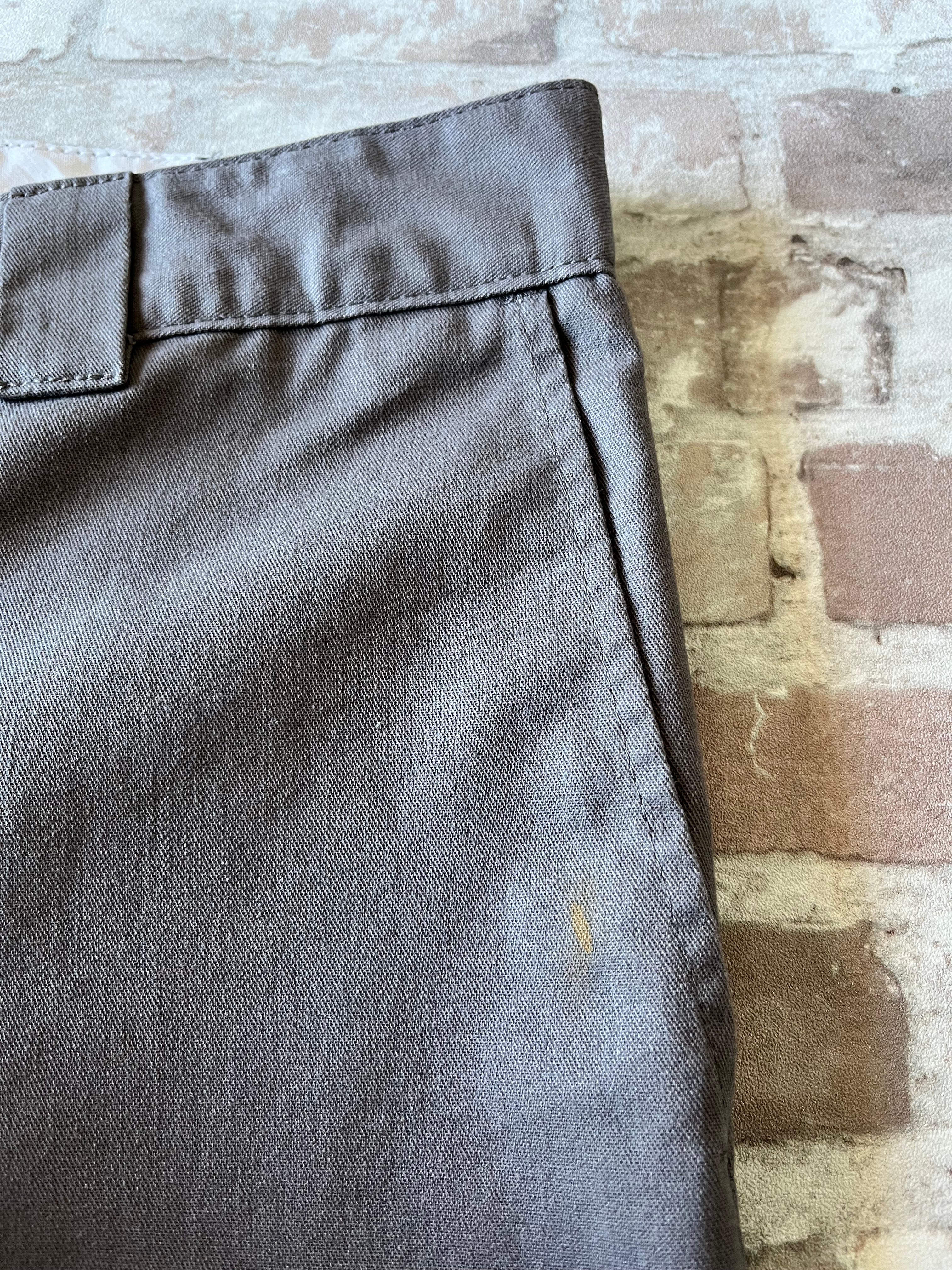 Gros plan sur une tache de peinture dorée unique sur la jambe d'un short Dickies gris de seconde main.