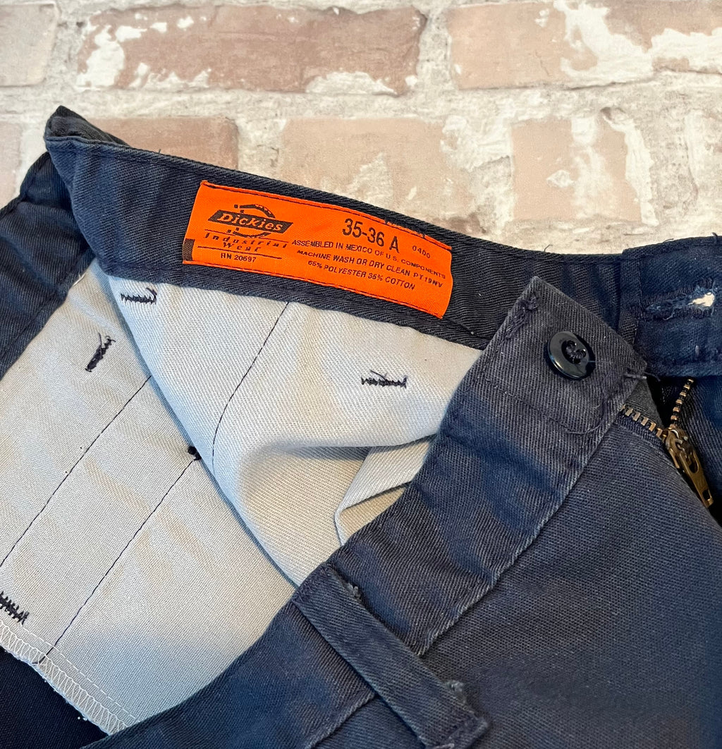 Gros plan sur l'étiquette vintage orange Dickies Industrial et les inserts élastiques de la ceinture d'un short de travail.