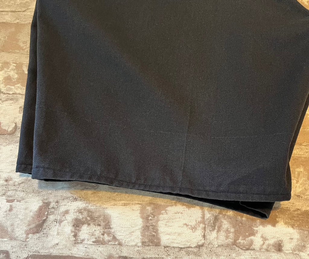 Gros plan sur le bas de jambe arrière présentant un fil tiré et la patine d'un short vintage Dickies marine.