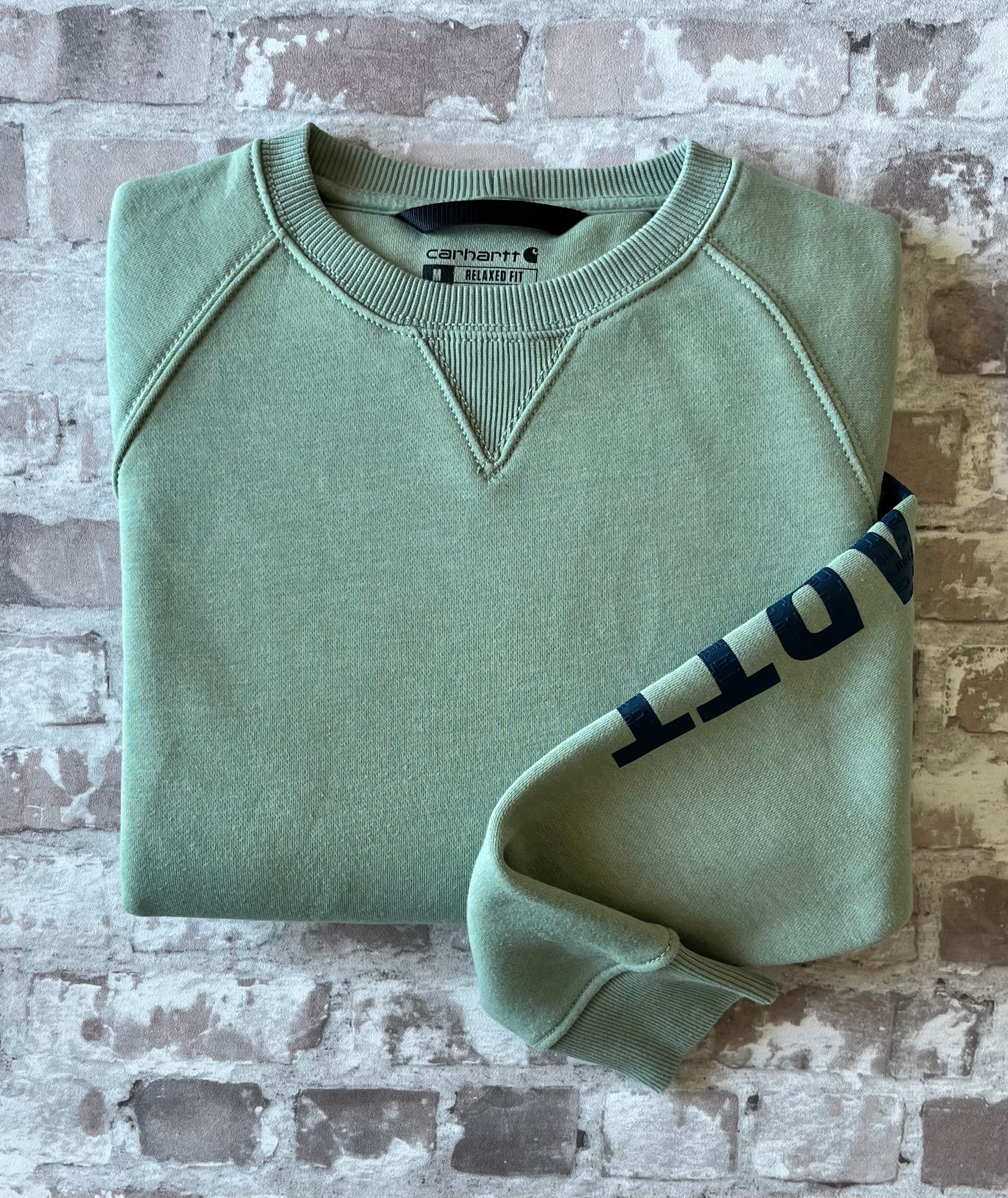Sweat col rond vintage Carhartt Force couleur vert sauge avec triangle de renfort au col, présenté plié à plat.