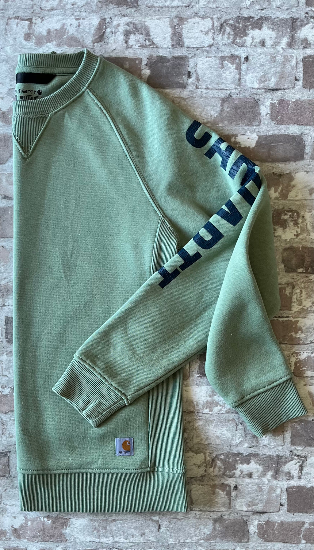 Sweat col rond vintage Carhartt Force couleur vert sauge avec triangle de renfort au col, présenté plié à plat, profil