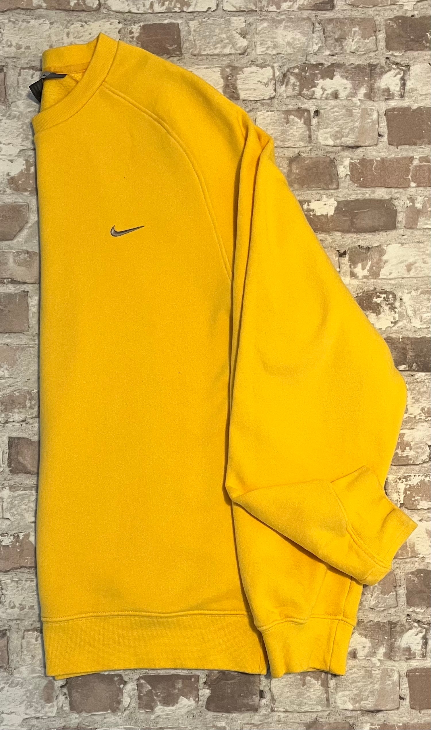 Sweat col rond vintage Nike jaune vif avec le logo Swoosh brodé sur la poitrine, présenté plié à plat, de profil