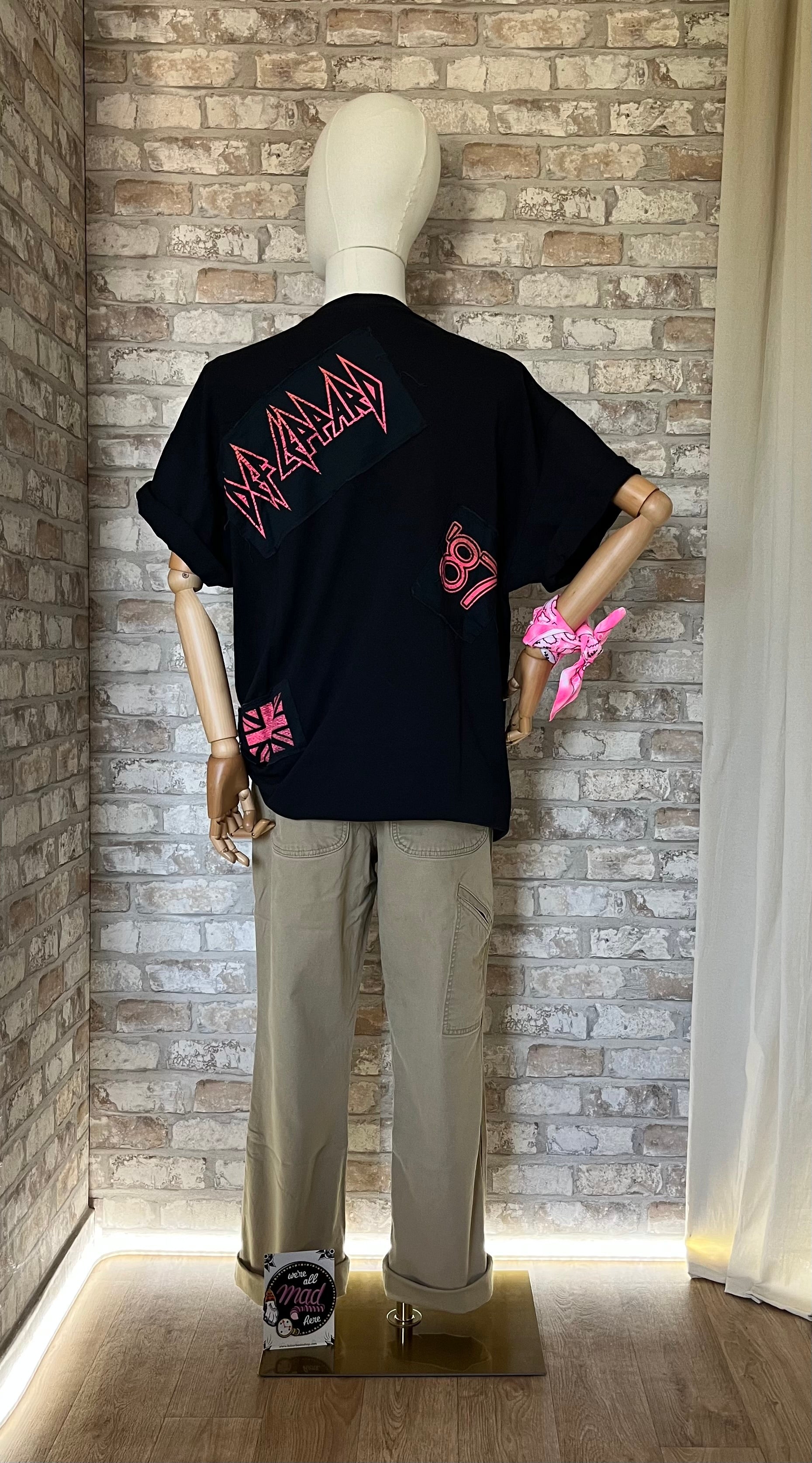 T-Shirt Def Leppard " Hysteria"  porté sur mannequin de dos avec un pantalon Carhartt , un bandana néon pink attaché au poignet et un Patch La Barbuda au sol