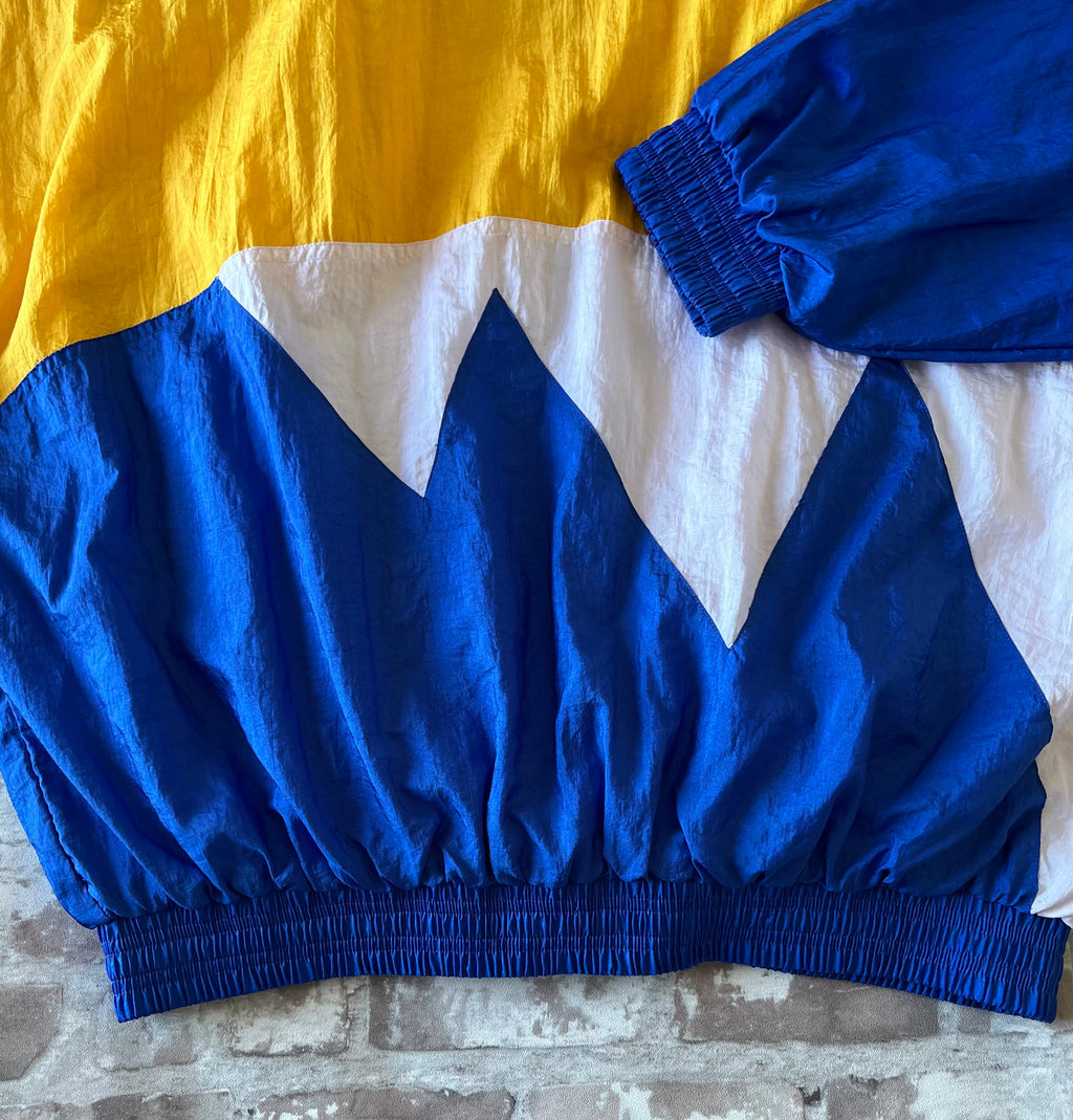 Veste coupe-vent vintage Pro Celebrity colorblock bleu royal et jaune avec broderie Mars Hill Athletics, présentée à plat, focus dos - ceinture.