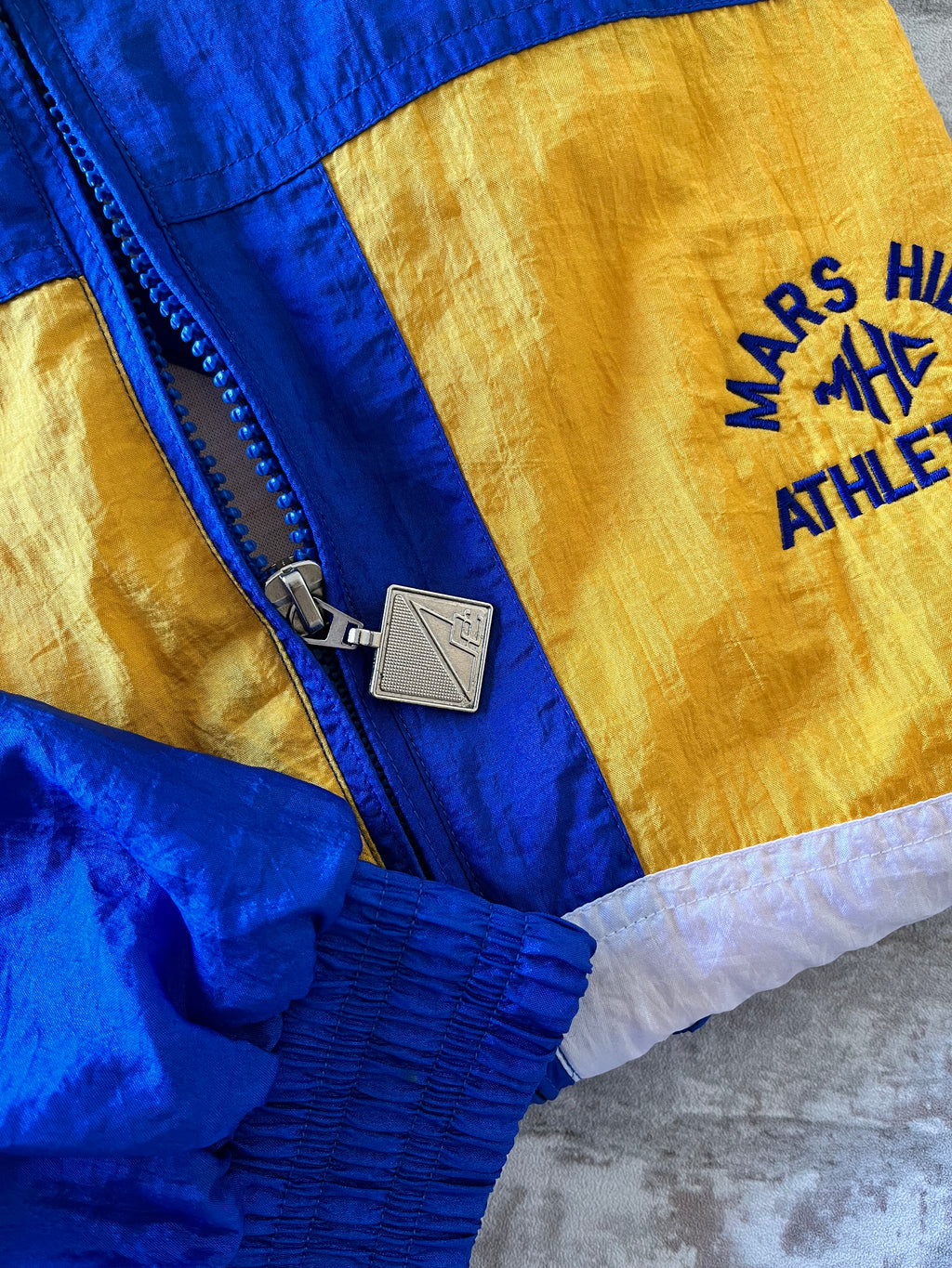 Veste coupe-vent vintage Pro Celebrity colorblock bleu royal et jaune avec broderie Mars Hill Athletics, présentée à plat, focus curseur et broderies.