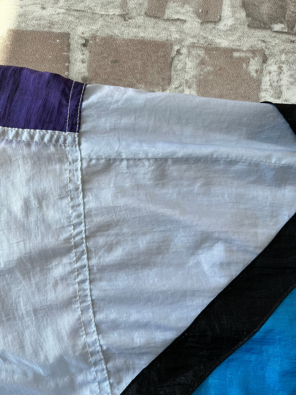 Veste rétro zippée Blair Boutique au motif colorblock néon et pastel, présentée pliée à plat, focus taches discrètes vertes sur épaule