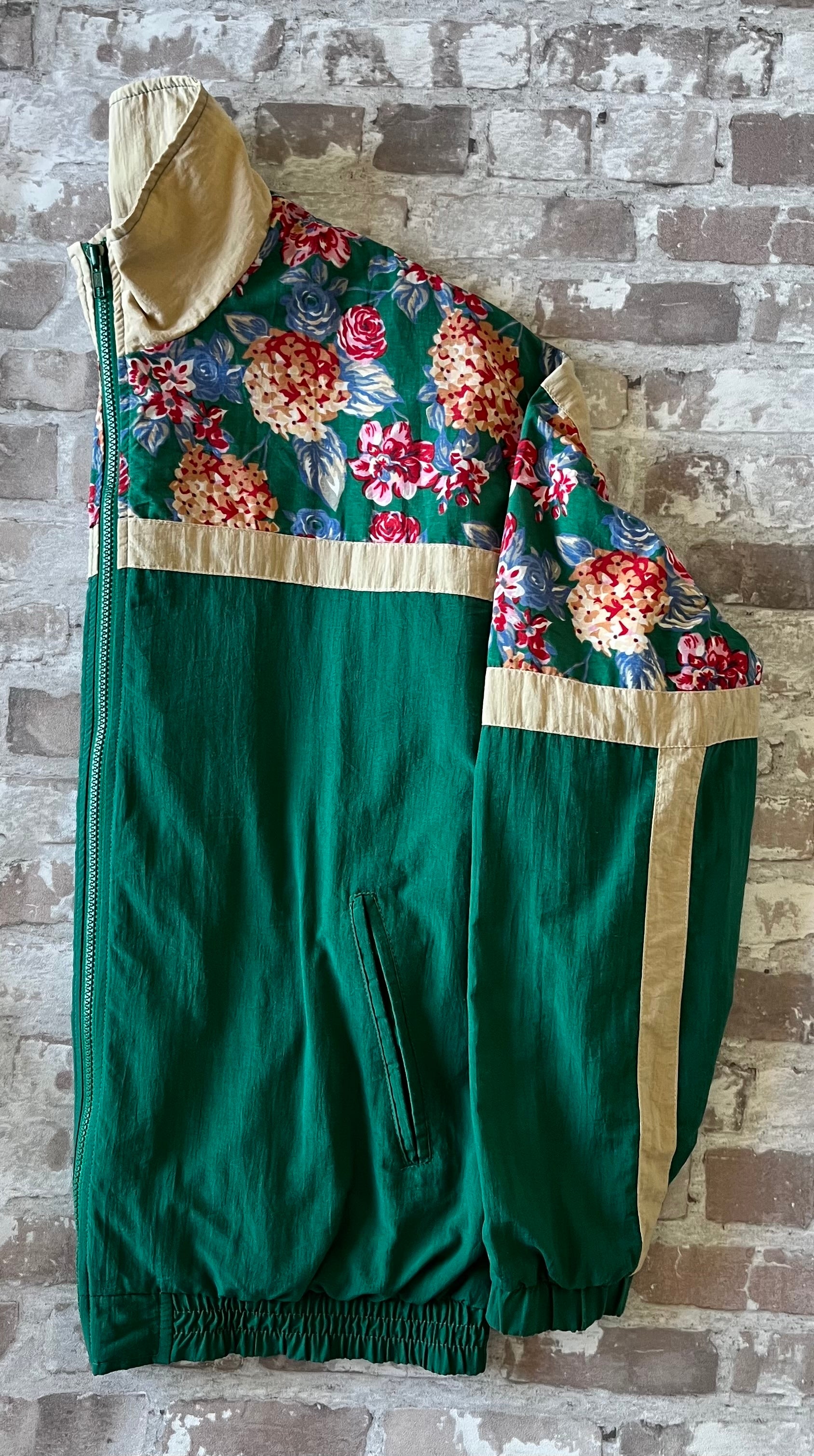 Veste coupe-vent vintage des années 90 couleur vert sapin avec empiècements à motifs de fleurs et bandes beiges, présentée à plat.