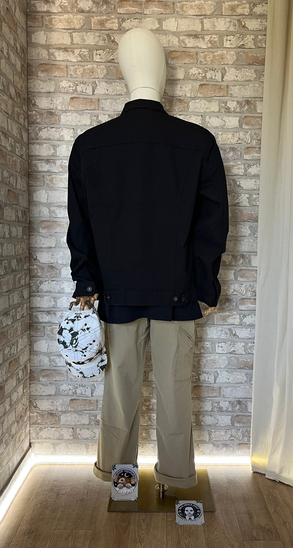 Veste en Jean Noire , Signature by Levi Strauss & Co portée sur mannequin avec pantalon Carhart,de dos, une casquette vinatge Adidas à la main et des patchs La Barbuda posés au sol.