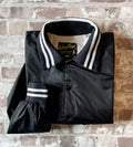 Veste coupe-vent vintage canadienne Kelsey Trail en nylon satiné noir avec boutons-pression et bords-côtes rayés, présentée pliée à plat.