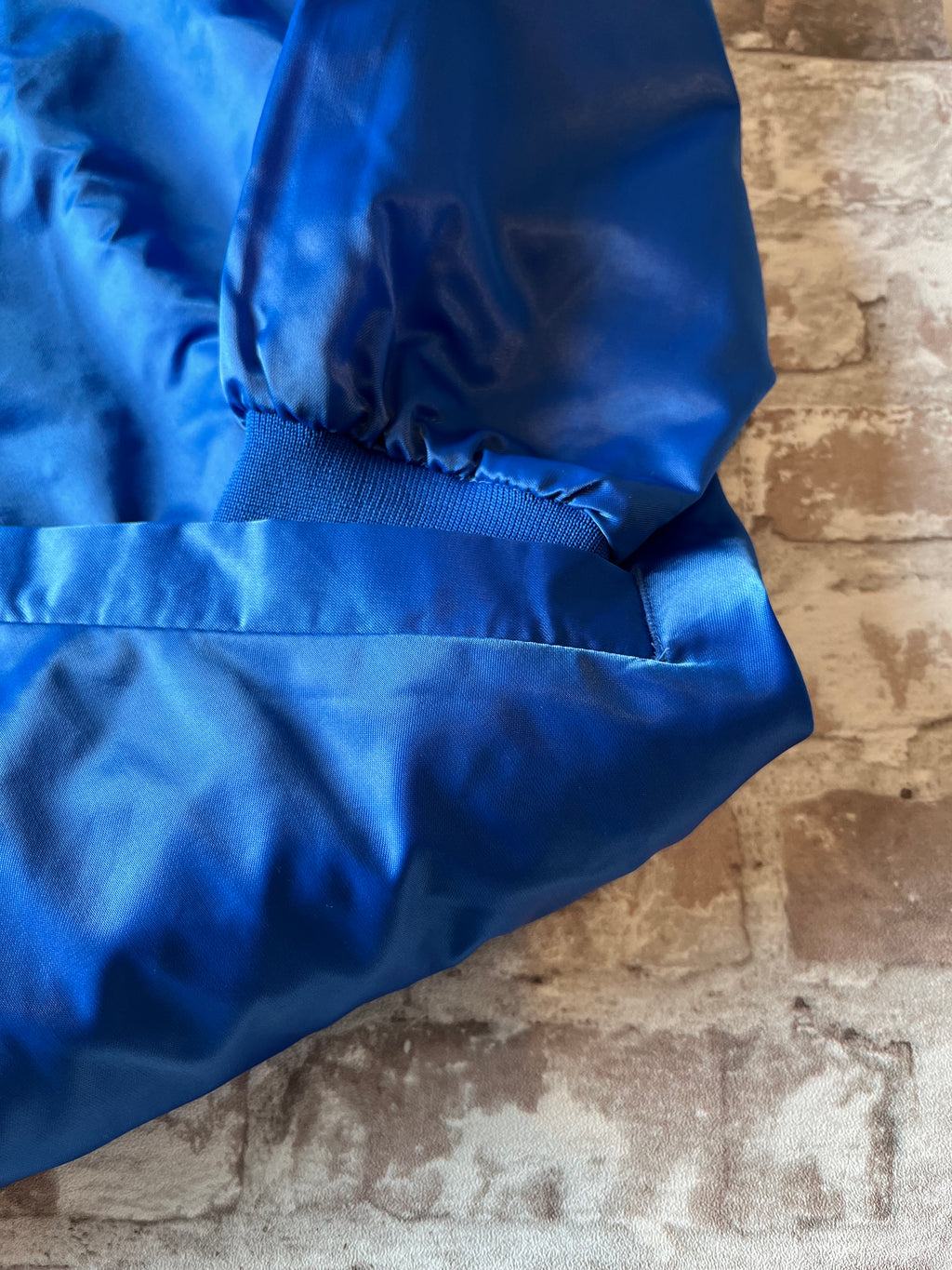 Veste de sport bomber léger rétro Cardinal bleu satiné avec fermeture à boutons-pression et écusson Campers On Mission, présentée à plat, focus poche