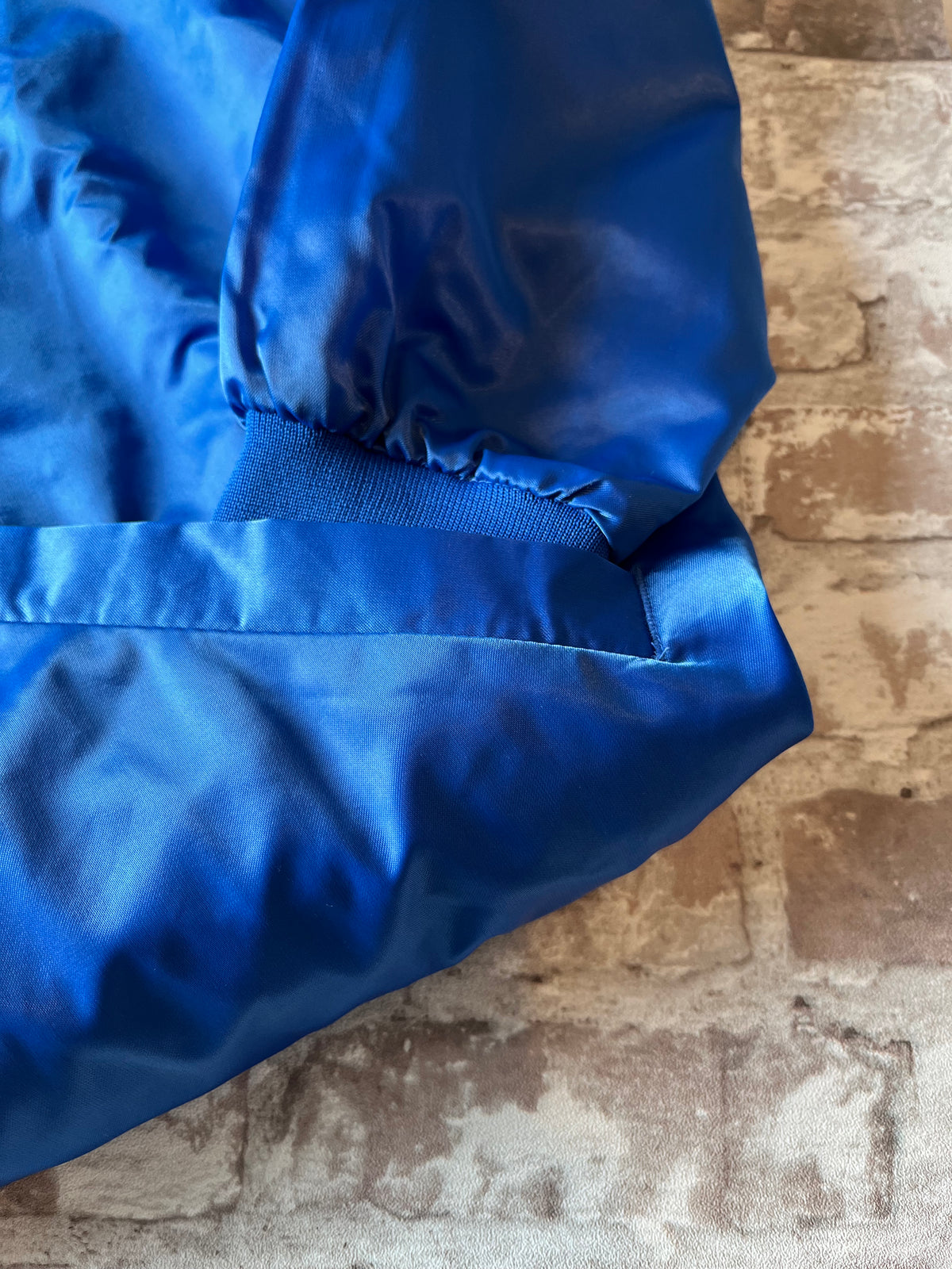 Veste de sport bomber léger rétro Cardinal bleu satiné avec fermeture à boutons-pression et écusson Campers On Mission, présentée à plat, focus poche