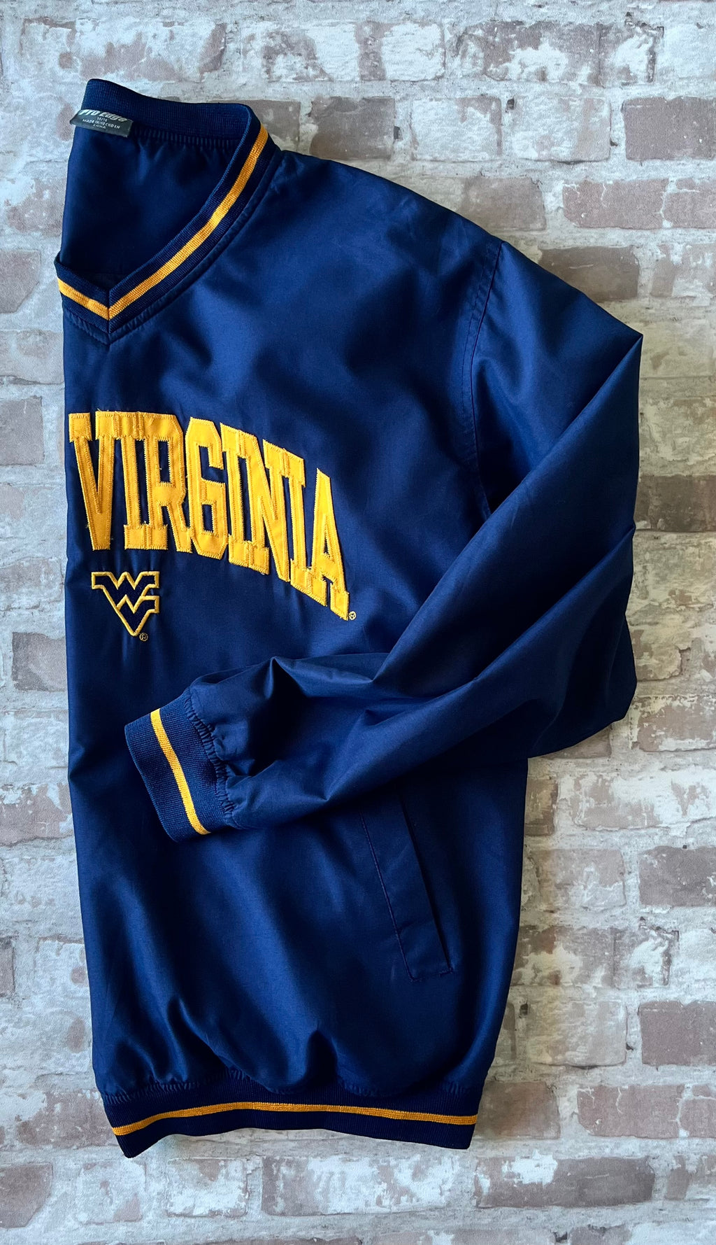 Veste de sport pullover rétro Pro Edge bleu marine avec broderie jaune West Virginia et col en V, présentée de profil à plat.
