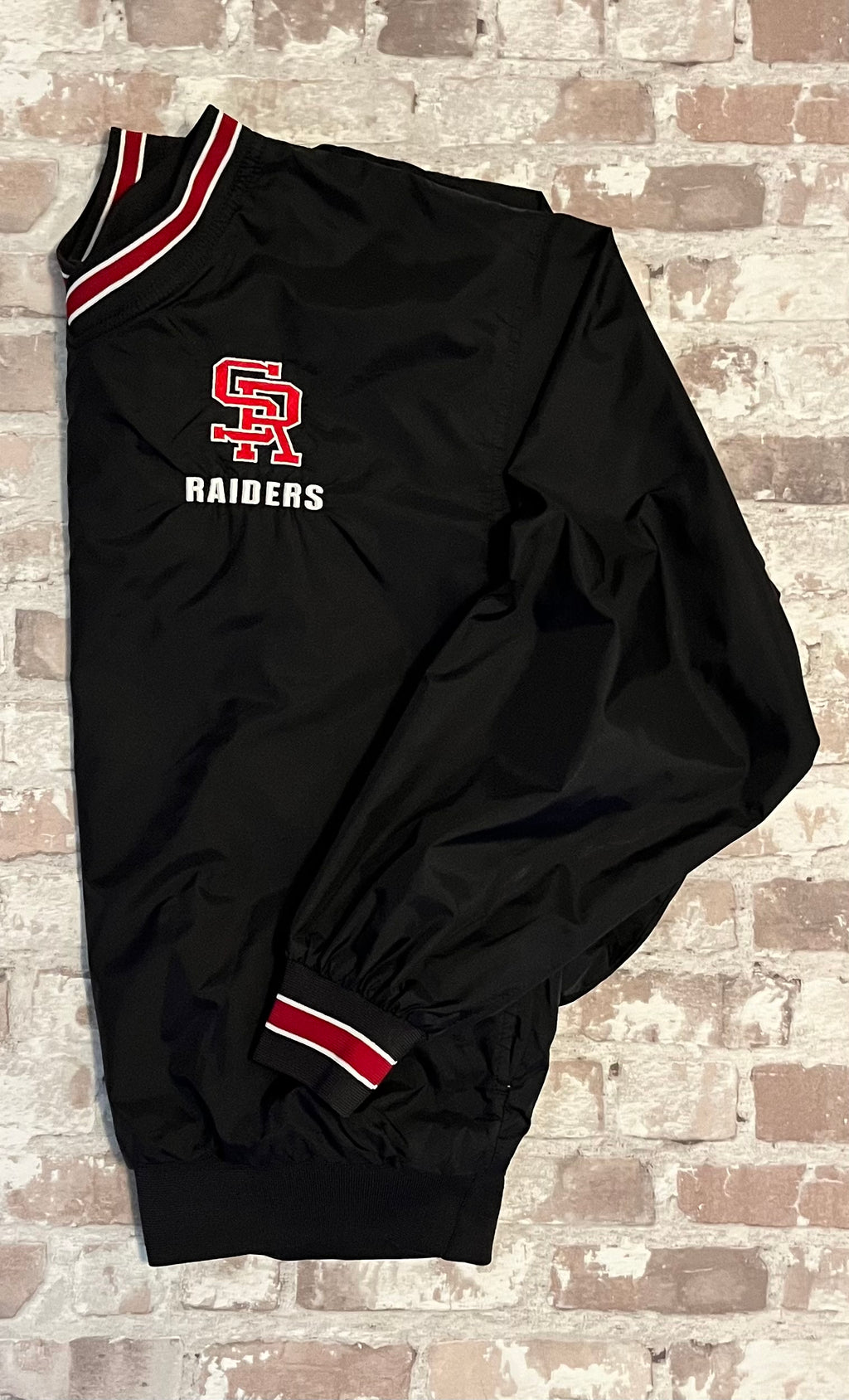 Veste de sport pullover rétro Sport-Tek noire avec broderie SR Raiders et bords-côtes rayés rouge et blanc, présentée à plat de profil
