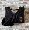 Veste de sport pullover vintage LA Loving noire au toucher peau de pêche avec broderie Buffalo et col en V marron, présentée à plat, pliée.