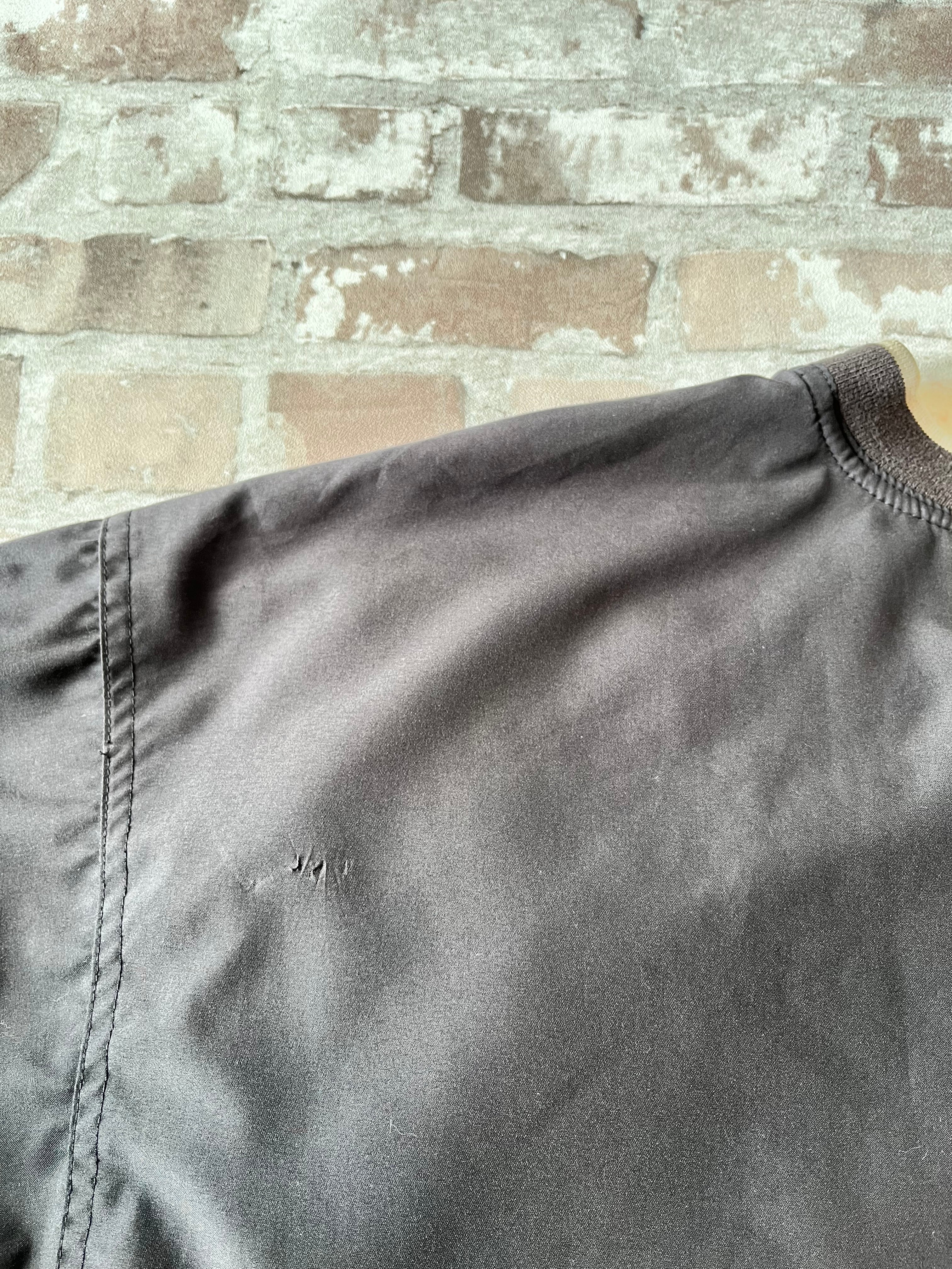 Veste de sport pullover vintage LA Loving noire au toucher peau de pêche avec broderie Buffalo et col en V marron, présentée à plat. Focus Accroc dos.