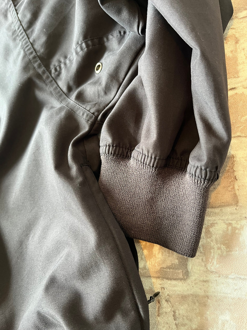 Veste de sport pullover vintage LA Loving noire au toucher peau de pêche avec broderie Buffalo et col en V marron, présentée à plat. 